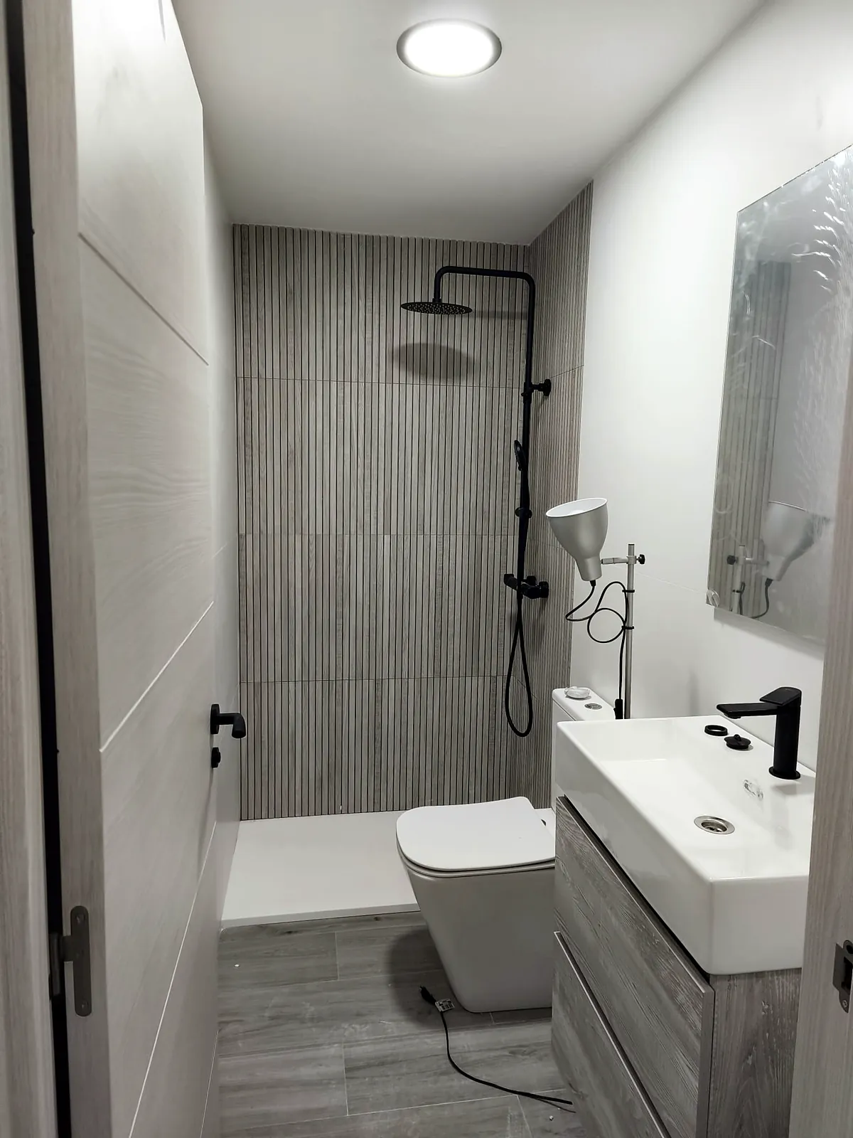 Baño con ducha negra y azulejo en relieve