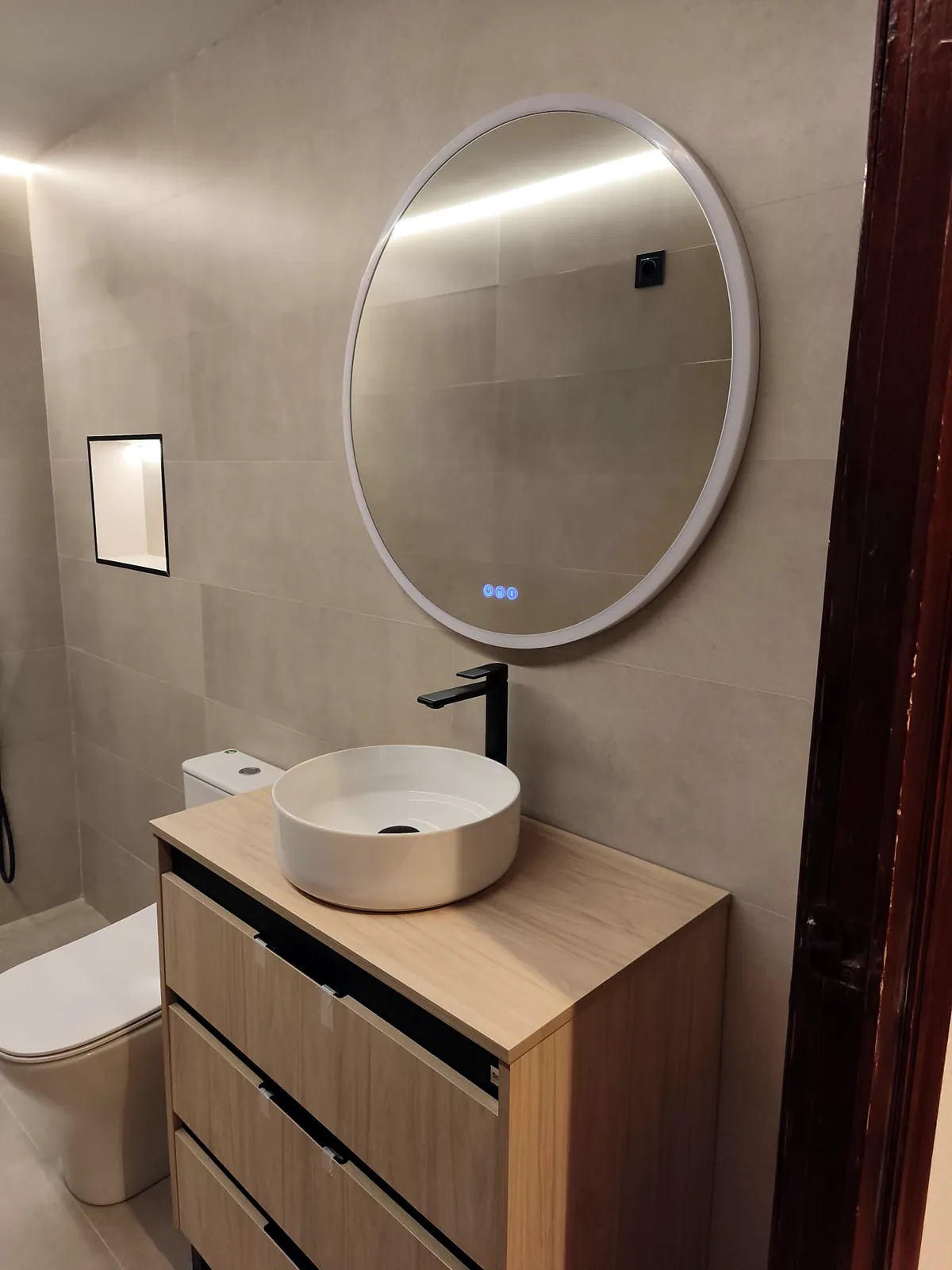 Lavabo de sobre encimera con mueble de madera y espejo iluminado